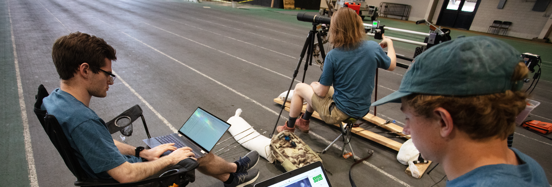 University scientists are plotting away on their laptops while in the background another looks through a spotting scope in a sports warehouse