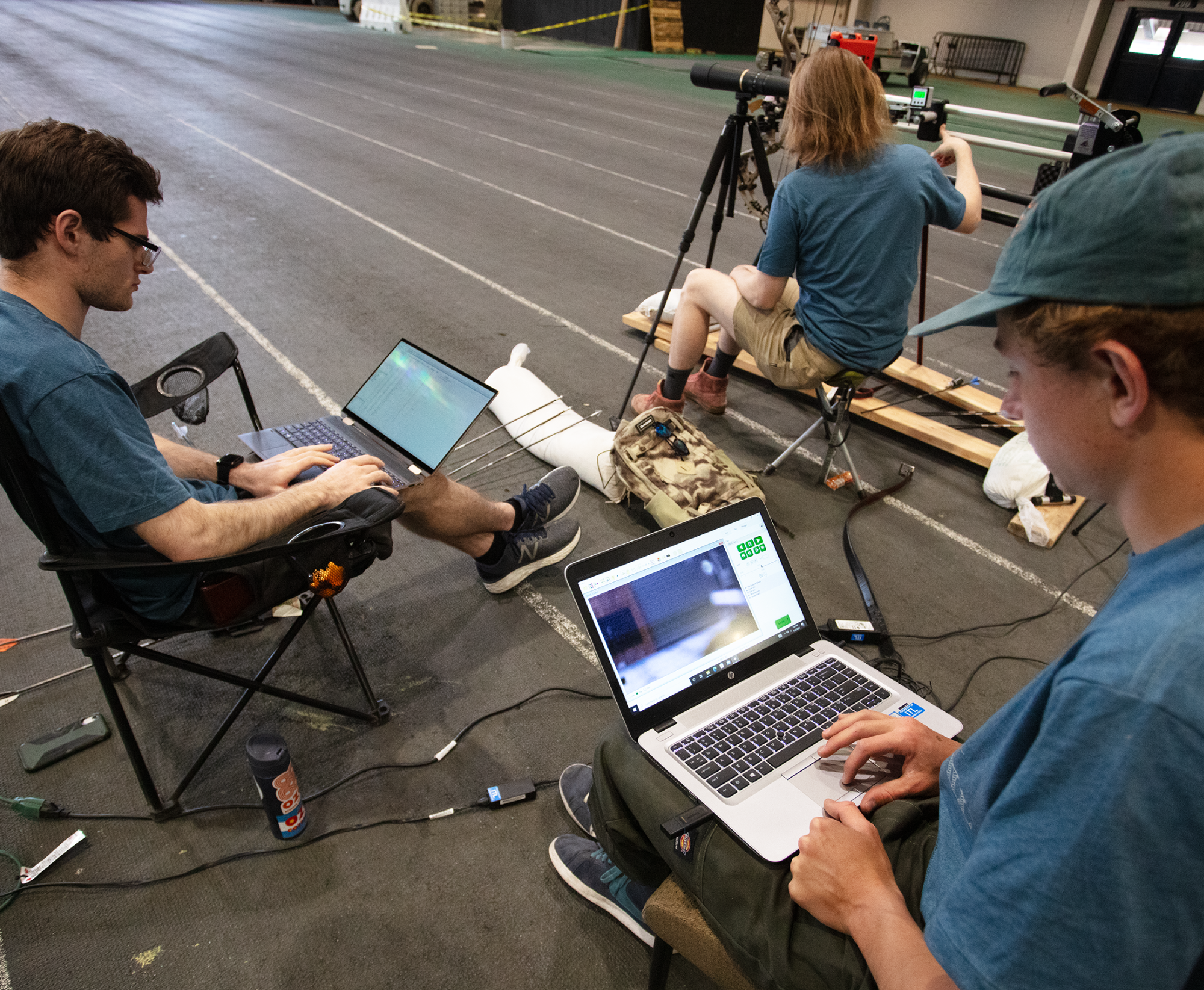 University scientists are plotting away on their laptops in a spreadsheet and some sort of a viewer program while in the background another looks through a spotting scope in a sports warehouse
