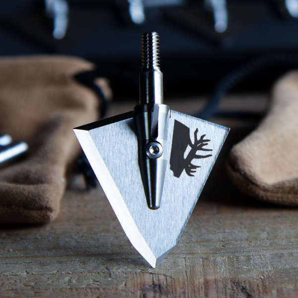 single bevel broadhead with elk engraving on a workbench